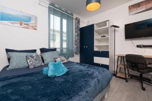 een slaapkamer met een blauw bed, een bureau en een televisie bij Santorin Îlot de Merville - Centre in Lorient