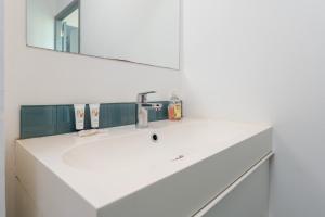 een badkamer met een witte wastafel en een spiegel bij Santorin Îlot de Merville - Centre in Lorient +16 foto's