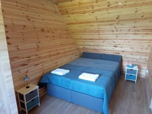a bedroom with a blue bed in a wooden wall at La Cabane Family in Rewal