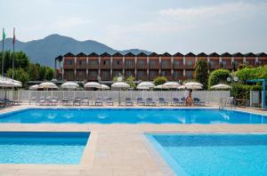 a pool with chairs and umbrellas in front of a hotel at Residence Il Patio in Iseo