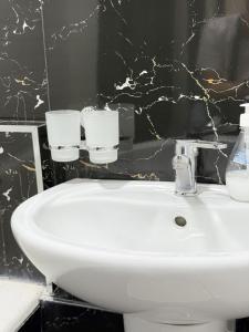 een badkamer met een witte wastafel en een zwarte muur bij Восточный уют 2 in Samarkand