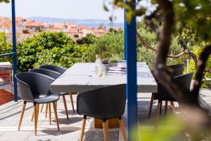 a table with chairs and a bottle of wine on a patio at Apartments Zambarlin in Komiža