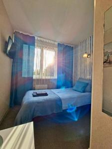 a bedroom with a blue bed with a window at Marynarski z kuchnią i łazienką in Koszalin