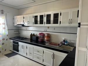 a kitchen with white cabinets and a sink at Villa MANSOURA avec piscine privative in Driouch