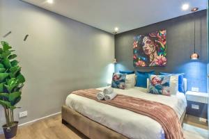 a bedroom with a large bed with a painting on the wall at St Martini Gardens Studio in Cape Town