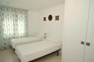 two beds in a room with white walls and curtains at Cala Gonzalez Superior Orange Costa in Alcossebre +20 photos