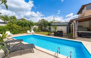 a swimming pool in a backyard with chairs around it at Beautiful Home In Prhati in Prhati