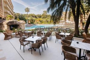 Un patio al aire libre con mesas y sillas y una piscina. en Hotel Jaime I, en Salou
