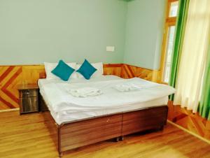 PalchānShree Dev Narayan Hotel的一张带白色床单和蓝色枕头的床 更多6张照片