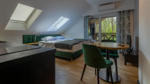 a bedroom with a bed and a table and green chairs at Villa Park Zwierzyniec in Zwierzyniec