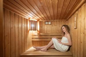 a woman is sitting in a sauna at Hotel Pannonia in Miskolc