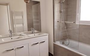 a bathroom with a sink and a shower with a mirror at Petite maison cosy avec jardin in Gujan-Mestras +14 photos