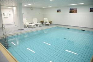 a large swimming pool with white chairs and a table at Das geräumige 2-Zimmer-Appartement in Westerland (Sylt)