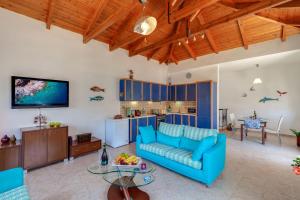 a living room with a blue couch and a kitchen at Kallisti Artemis in Kávallos