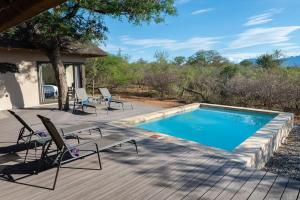 una piscina en una terraza de madera con sillas alrededor en Villa Marula, en Hoedspruit