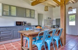 a kitchen with a wooden table and blue chairs at Athentique Maison Normande in Vénesville