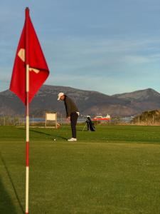 a person playing golf on a green with a red flag at Attractive and central apartment in Ålesund