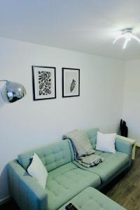 un divano blu in soggiorno con due foto sul muro di Luxurious 2 beds Urban Glint by GOO Living a Spon End