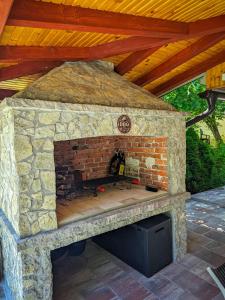 a stone fireplace in a patio with a wooden roof at Vikendica Stella in Bihać