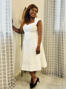 a woman in a white dress standing next to a window at Les Appartement meublés BELLE et BEAU à Yaoundé Ngousso , lieu dit, deux étages in Yaoundé