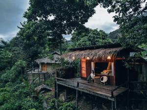 a person sitting on a porch of a hut at อะบู้ศรีโฮมสเตย์ in Ban Huai Khai