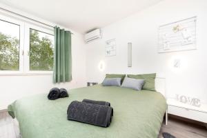 a bedroom with a green bed with two towels on it at Apartman Babich in Rovinj