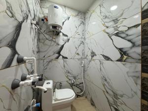 a bathroom with a white toilet and marble walls at Guruvayur Dham 200 mtr from Mathura Railway Station in Mathura +23 photos