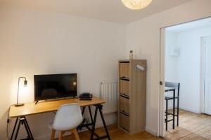 een kamer met een bureau, een tv en een tafel bij les loges de jeanne in Orléans
