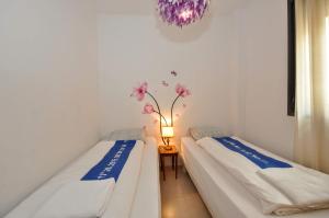two beds in a room with a lamp and flowers on the wall at Apartment Verano Go2lloret in Lloret de Mar