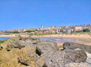 a group of rocks on a beach with a city in the background at Casa Santiago in Gela