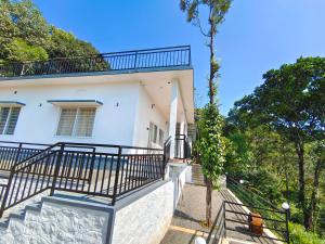 a white house with stairs and a balcony at Robin's Paradise Deluxe Villa in Vagamon