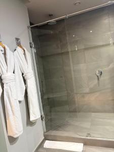 a glass shower stall with white towels on hooks at Hotel Le Rocher Marrakech in Marrakesh +33 photos