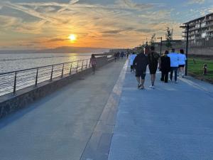 a group of people walking along a pier at sunset at Karim's House in Portici +7 photos