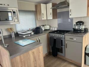 een keuken met een spoelbak en een fornuis bovenste oven bij Ardmachree in Burton Bradstock