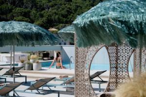a woman in a bikini is sitting in lounge chairs next to a pool at El Vicenç de la Mar - Adults Only - Over 12 in Pollença +37 photos