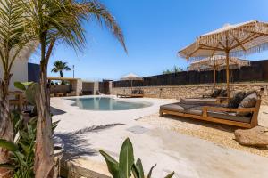 a swimming pool with chairs and umbrellas in a yard at Cala Coralli in Syracuse