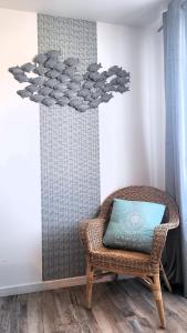 a wicker chair with a blue pillow in a room at Gîte KERBOURC'H charmant et confortable, mer et plages à 3km, Ploudalmézeau in Ploudalmézeau