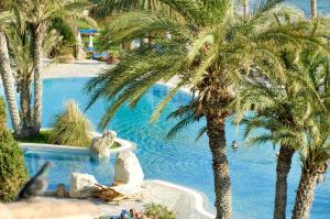 a swimming pool with palm trees in a resort at Coral Beach Hotel & Resort Cyprus in Coral Bay