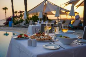 a table with plates of food and glasses of wine at Coral Beach Hotel & Resort Cyprus in Coral Bay