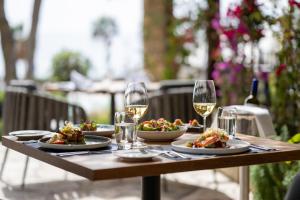 a wooden table with plates of food and glasses of wine at Coral Beach Hotel & Resort Cyprus in Coral Bay