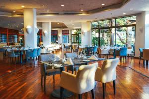 a dining room with tables and chairs and windows at Coral Beach Hotel & Resort Cyprus in Coral Bay