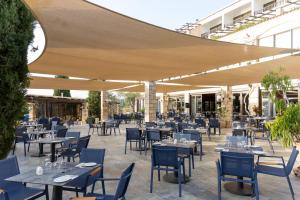 an outdoor restaurant with tables and chairs and awnings at Coral Beach Hotel & Resort Cyprus in Coral Bay
