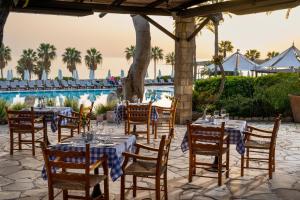 a restaurant with tables and chairs in front of a pool at Coral Beach Hotel & Resort Cyprus in Coral Bay