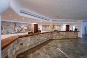 a man standing in a lobby with a bar at Coral Beach Hotel & Resort Cyprus in Coral Bay