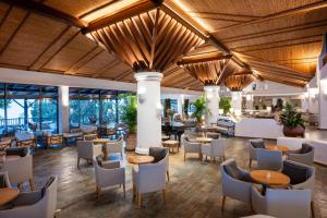 a restaurant with wooden ceilings and tables and chairs at Coral Beach Hotel & Resort Cyprus in Coral Bay