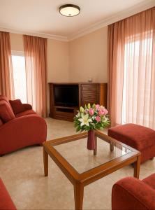 a living room with a vase of flowers on a coffee table at Appartement entier in Paralia Katerinis
