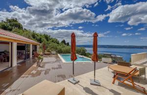 a patio with two umbrellas and a swimming pool at Villa Olive retreat in Krilo