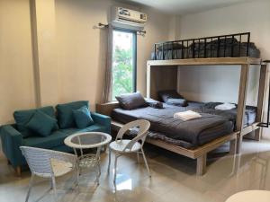 a bedroom with a bunk bed and a couch and chairs at ขุนโลหะ K̄hun loh̄a in Phuket