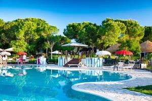 a swimming pool with umbrellas and chairs and tables at Il Podere Del Germano Reale in Coriano