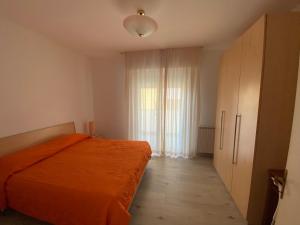 a bedroom with an orange bed and a large window at Casa Eva in Bibione